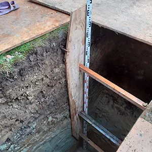 A hole in the ground with a measuring tape on it.